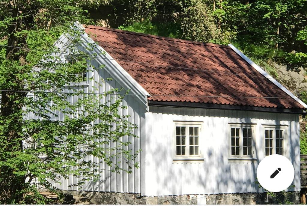 una pequeña casa blanca con techo rojo en Koselig lite hus nær sentrum en Arendal