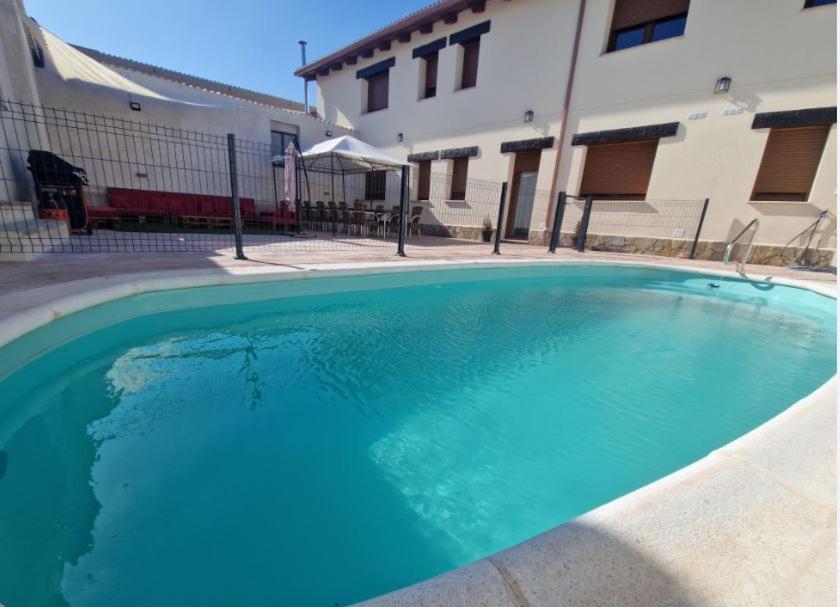uma grande piscina azul em frente a um edifício em Casa Rural Villa Cárcavas em Maello