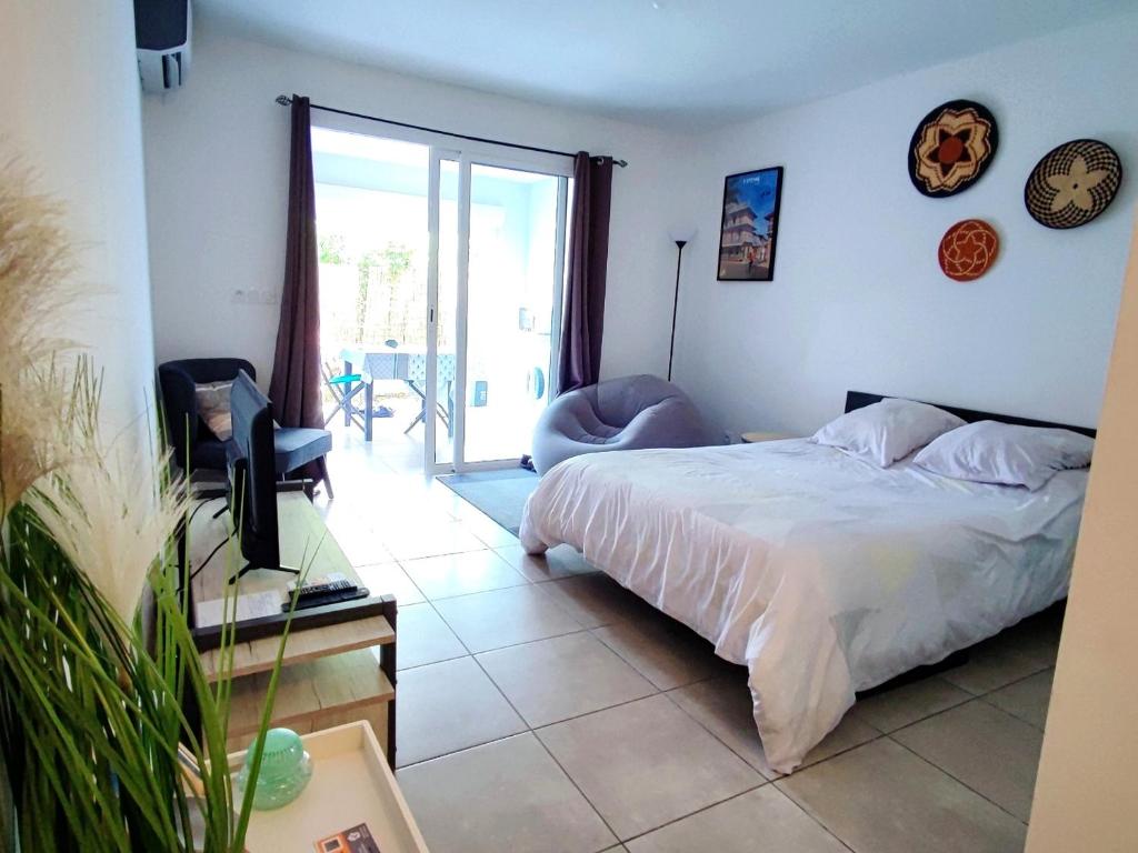 a bedroom with a bed and a sliding glass door at Studio confort avec jardinet in Montjoly