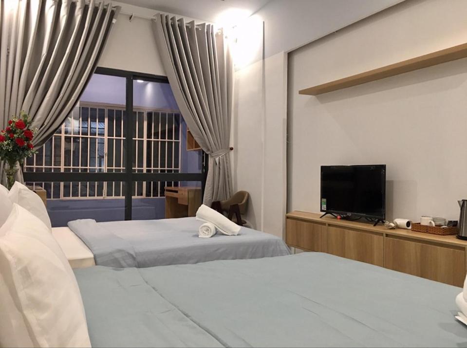 ein Hotelzimmer mit 2 Betten und einem Flachbild-TV in der Unterkunft Saigon Cozy Home " At BuiVien Walking Street " in Ho-Chi-Minh-Stadt