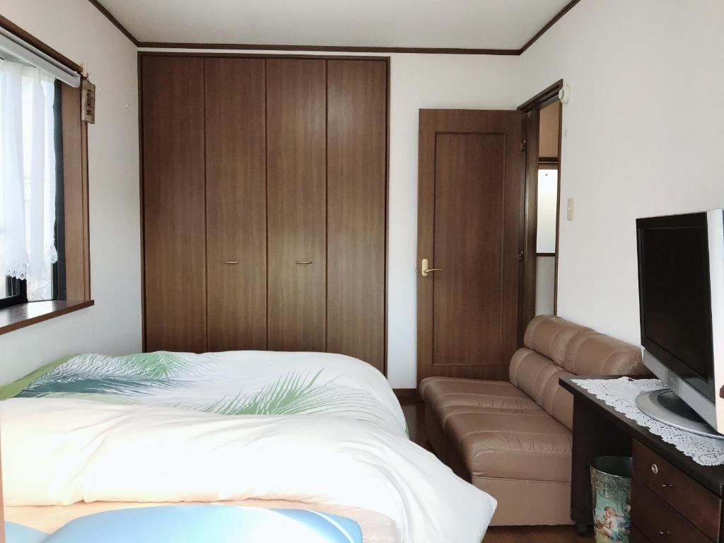 a bedroom with a bed and a couch and a flat screen tv at friendly 民宿 in Sagamihara