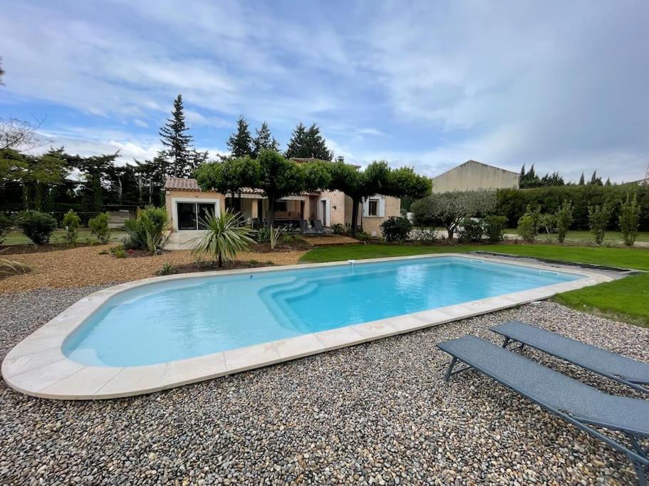 a large swimming pool with two chairs and a house at Villa au calme avec piscine chauffée in Châteaurenard