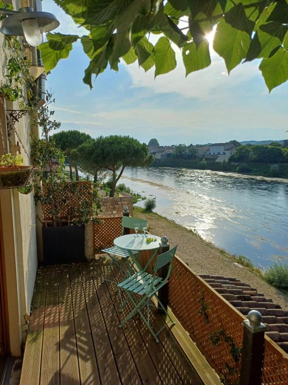 balkon ze stołem i krzesłami oraz widokiem na rzekę w obiekcie The Riverview Loft w mieście Sainte-Foy-la-Grande