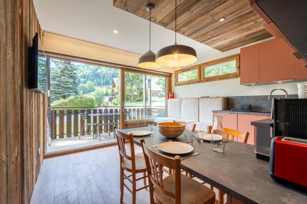 une cuisine avec une table et des chaises ainsi qu'une grande fenêtre dans l'établissement Riante 6 - Appartement proche du village et des pistes, à La Clusaz