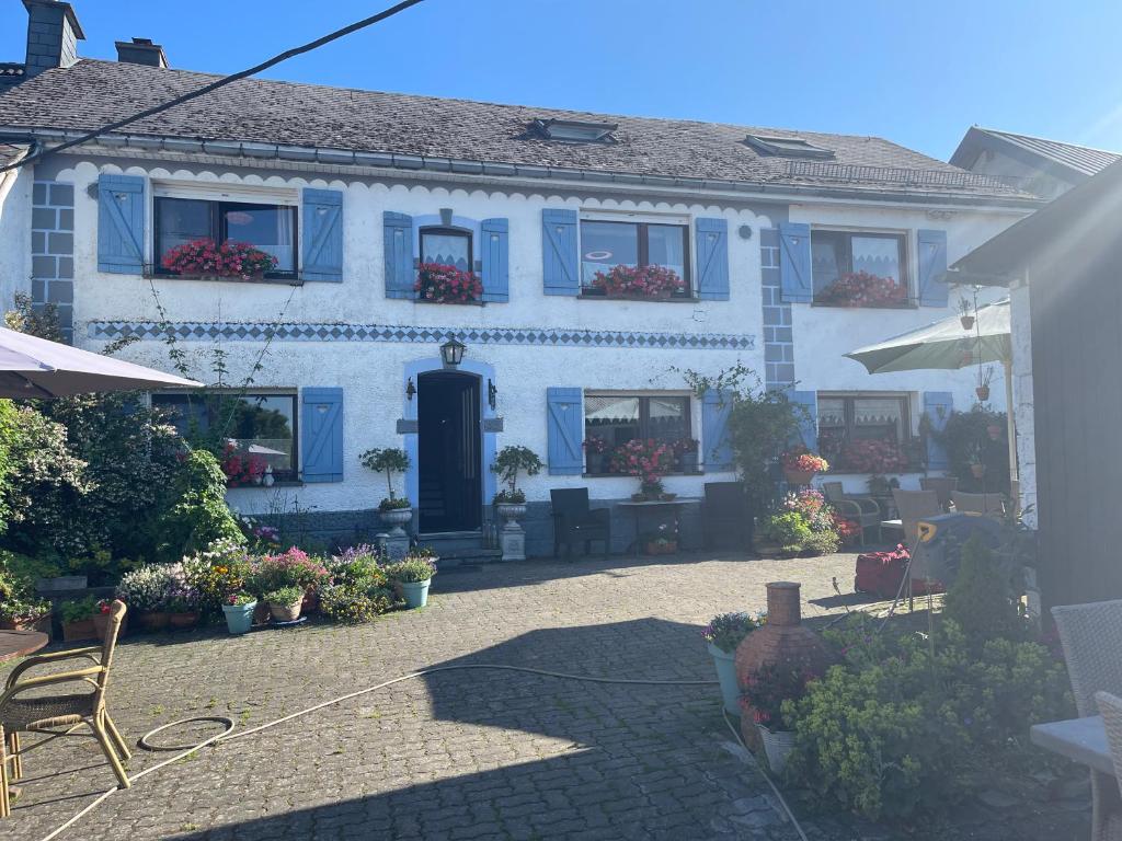 ein weißes Haus mit blauen Fenstern und einer Terrasse in der Unterkunft B&B De Eifelhoeve in Herresbach