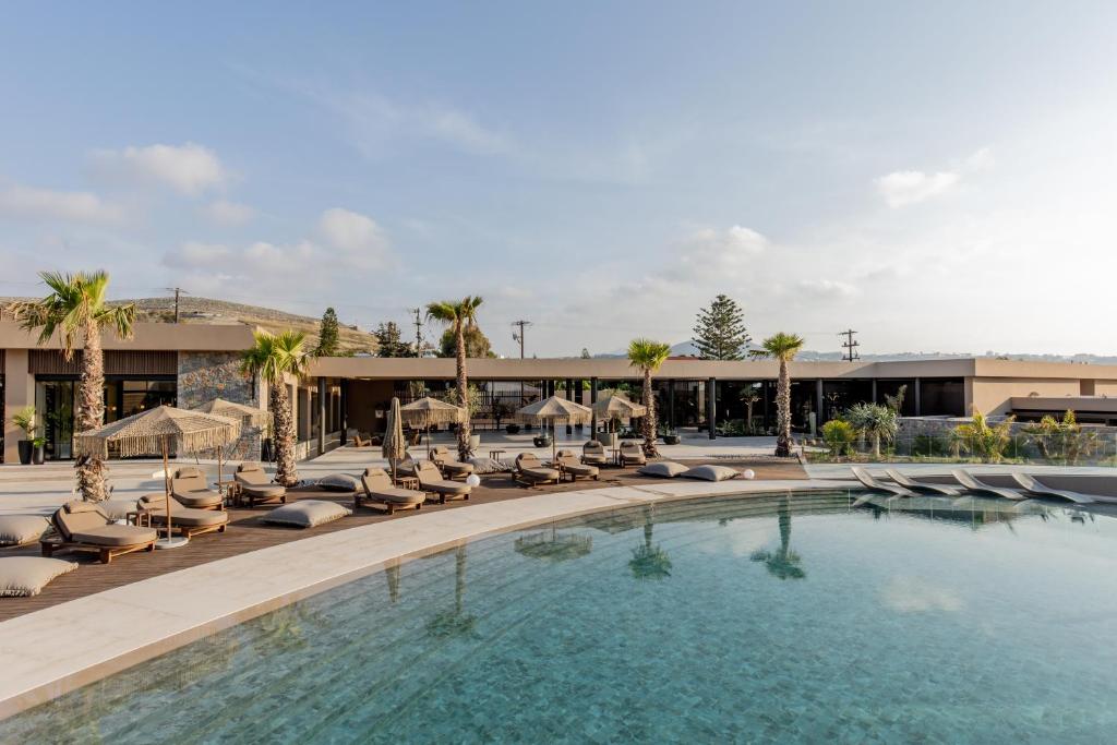 une piscine avec des chaises longues et un hôtel dans l'établissement Pnoe Breathing Life - Adults Only, à Karteros