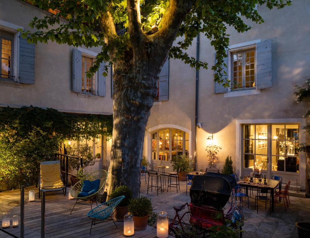 un patio con un árbol, sillas y velas en La Maison Sur La Sorgue - Esprit de France, en LʼIsle-sur-la-Sorgue