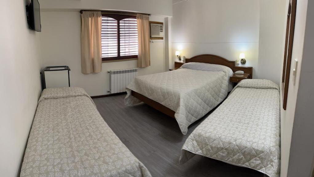 Cette chambre comprend 3 lits et une fenêtre. dans l'établissement Hotel Catedral, à Luján