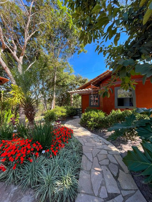 a garden with red flowers in front of a house at Chalés Cores da Mata in Tiradentes