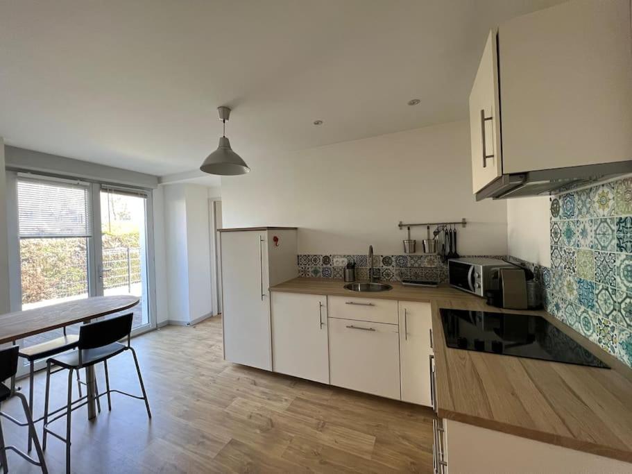 a kitchen with white cabinets and a table and chairs at La terrasse des Thermes, Jura in Lons-le-Saunier