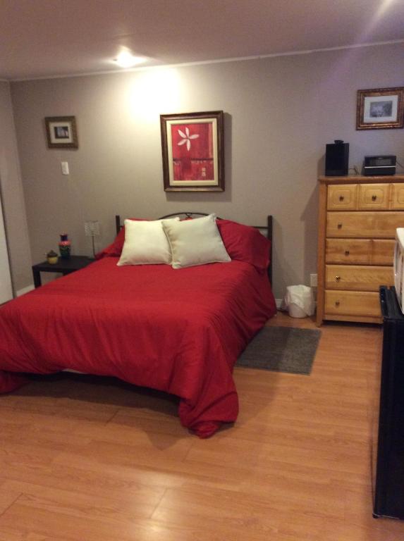 a bedroom with a bed with a red blanket and a dresser at Chambre confortable in Sherbrooke