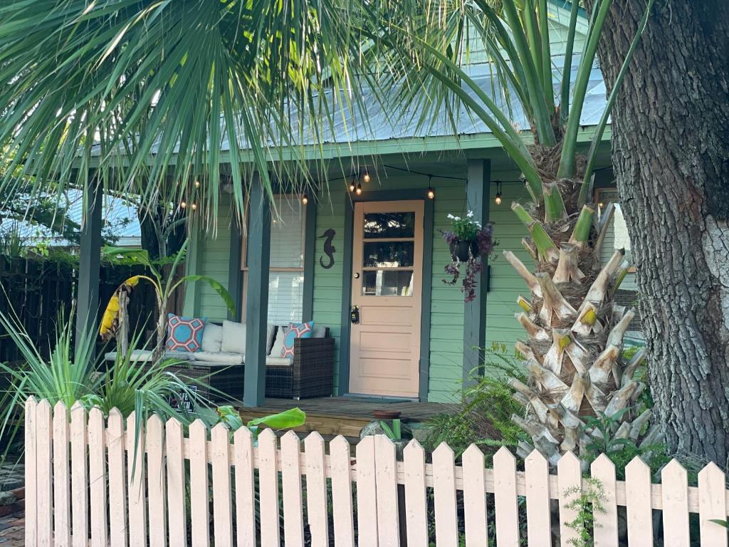 una casa verde con una valla blanca delante de ella en 3BR/3BA Charming Key West Style Home in Downtown Saint Augustine en Saint Augustine