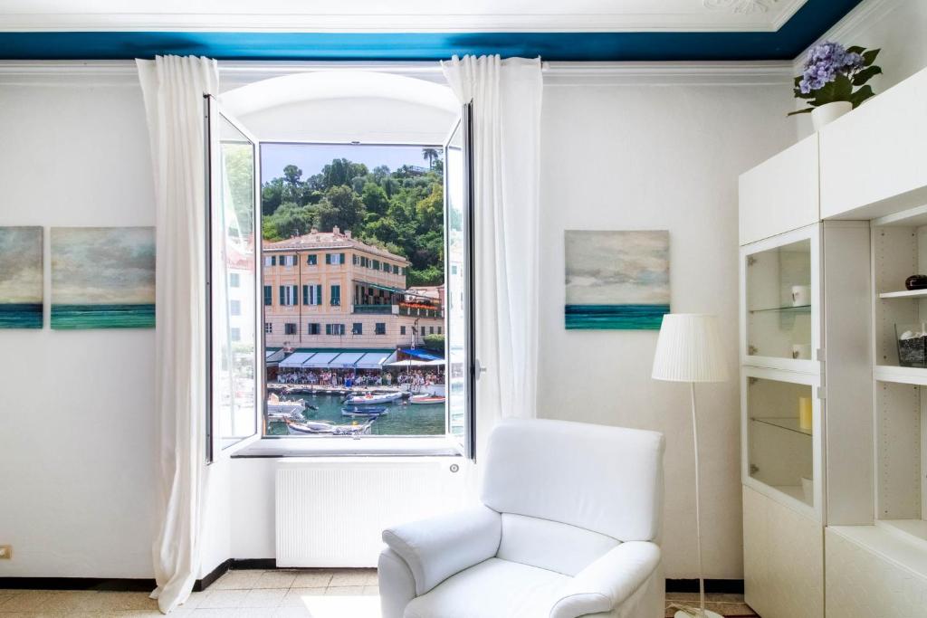 a living room with a white chair and a window at Blue by PortofinoHomes in Portofino