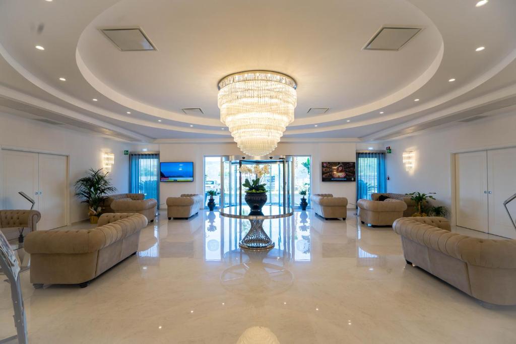 カタンツァーロ・リドにあるPM Hotelのソファと大きなシャンデリアが備わる広いロビー