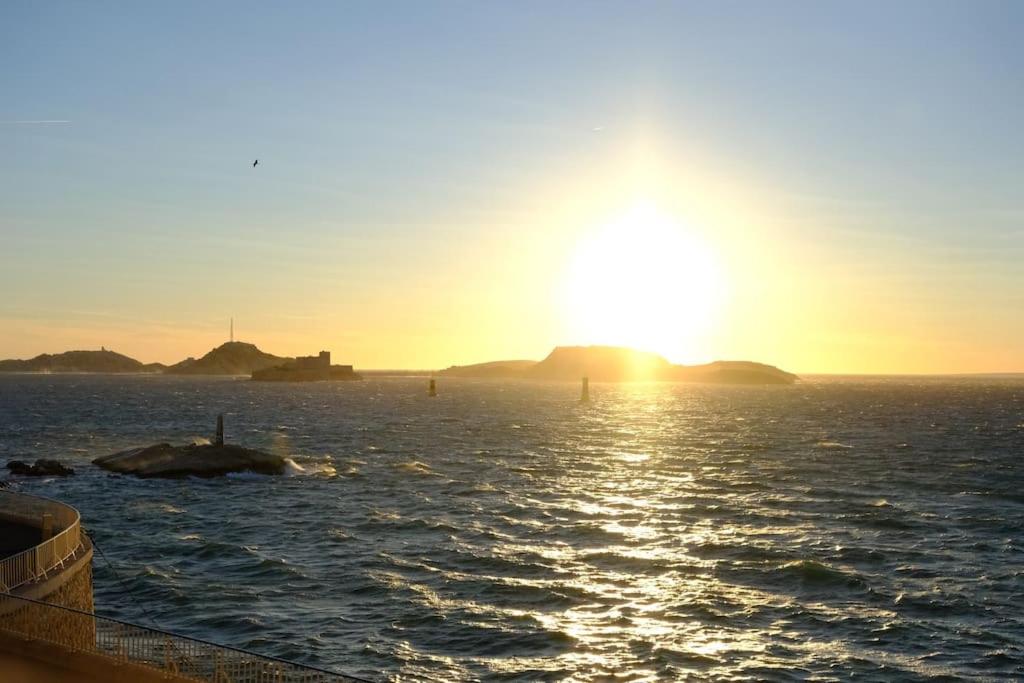 un coucher de soleil sur un plan d'eau avec des îles au loin dans l'établissement Appartement de standing vue mer, à Marseille