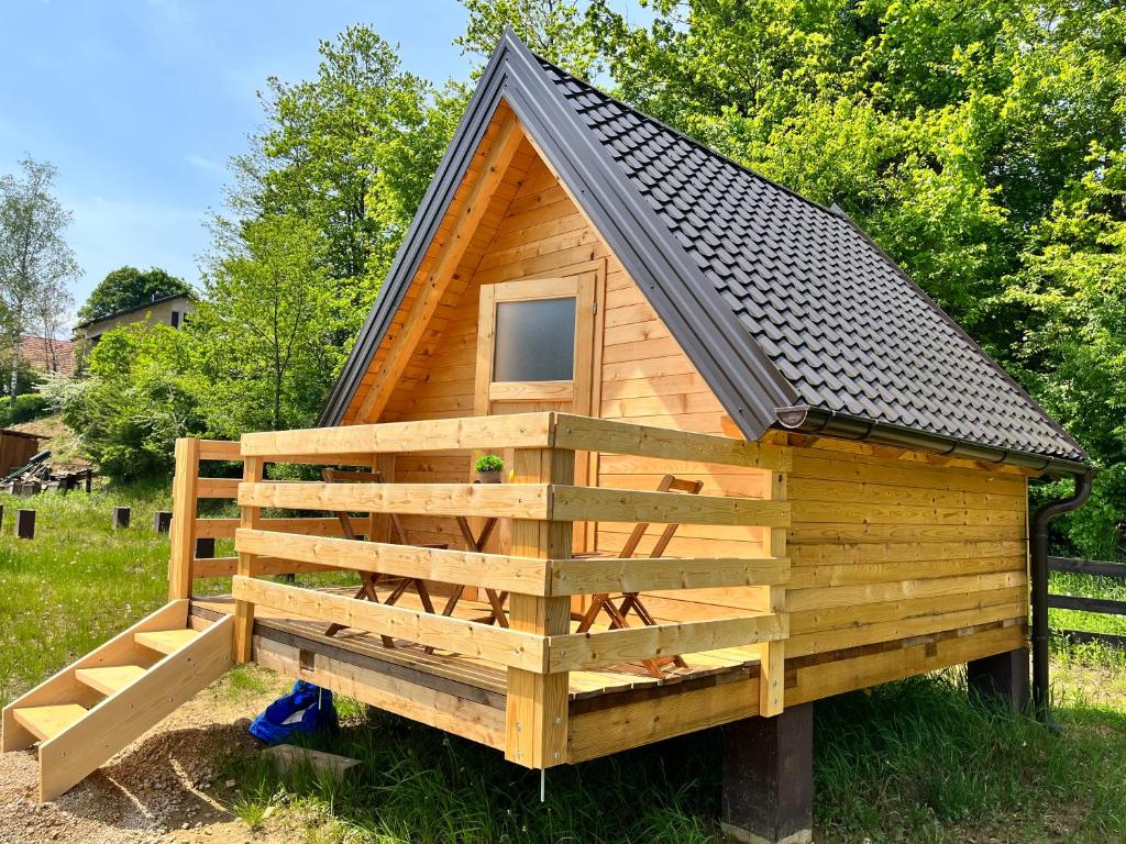a small wooden cabin with a black roof at Green River - robinzonski kamp in Duga Resa