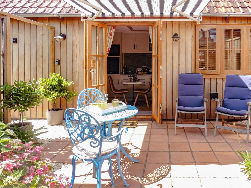 un patio con sillas azules y una mesa en Copse Lodge en Eling