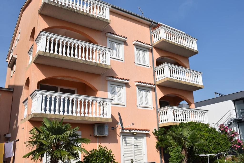 ein orangefarbenes Gebäude mit weißen Balkonen und Palmen in der Unterkunft Apartments Lavanda in Crikvenica
