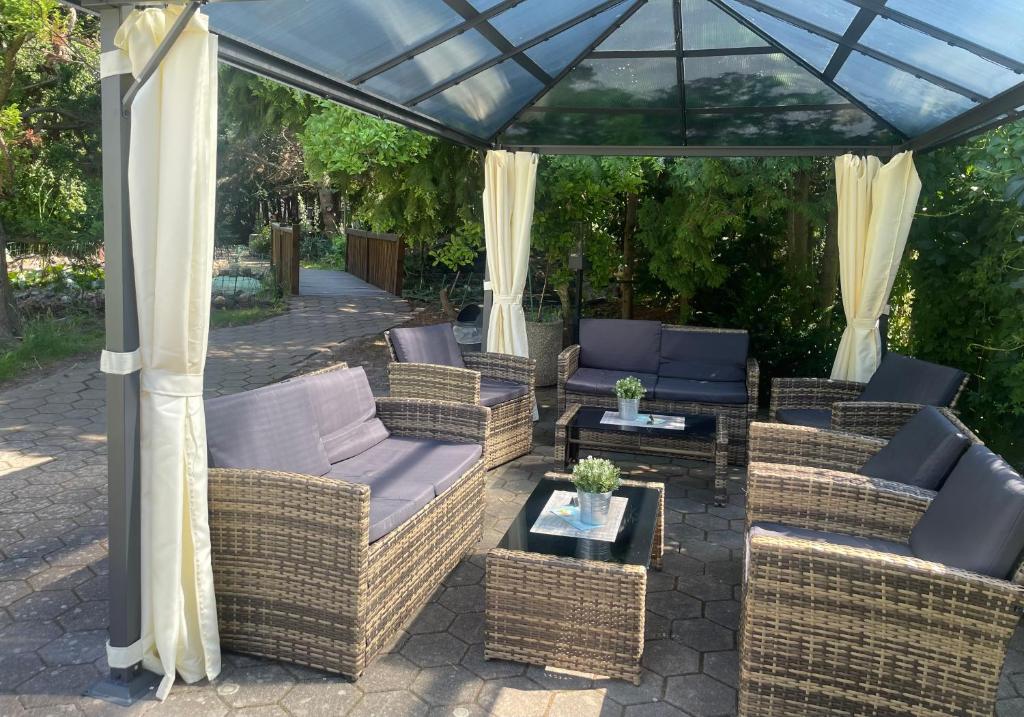 a patio with wicker furniture under a gazebo at Harzhotel Warnstedter Krug in Thale