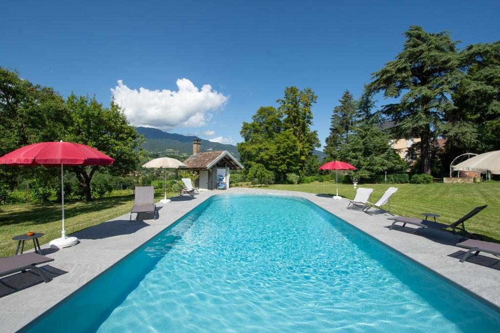 basen z leżakami i parasolami na dziedzińcu w obiekcie Domaine des Granges Longes w mieście Les Marches