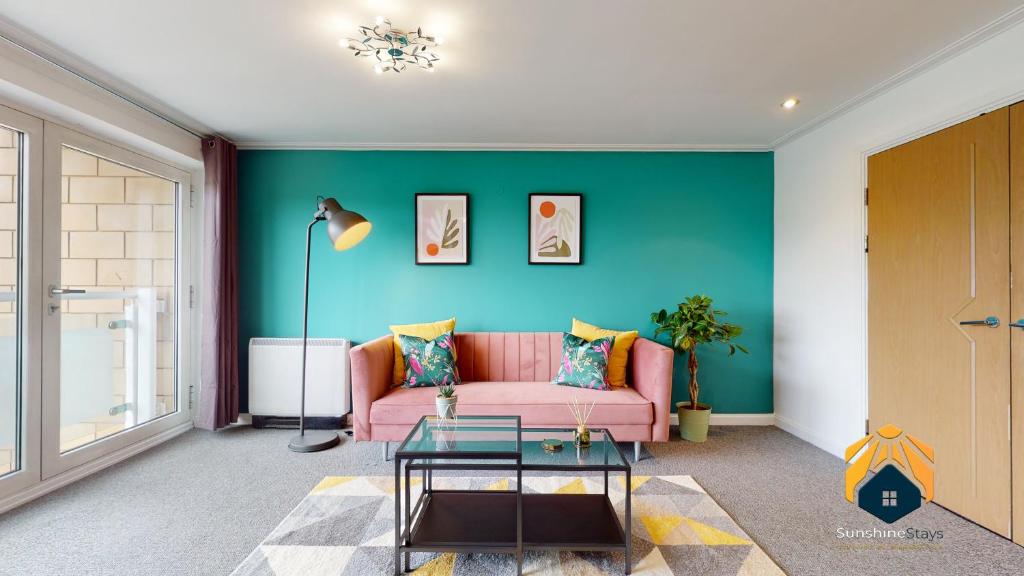 - un salon avec un canapé rose et un mur vert dans l'établissement Stunning Cardiff City Apartment! Sleeps 8, à Cardiff