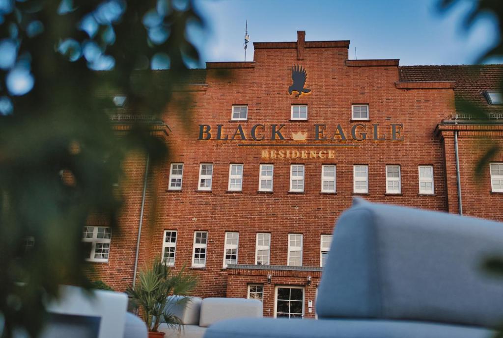 a red brick building with a black eagle sign on it at Residence Black Eagle Lubmin Strand in Lubmin