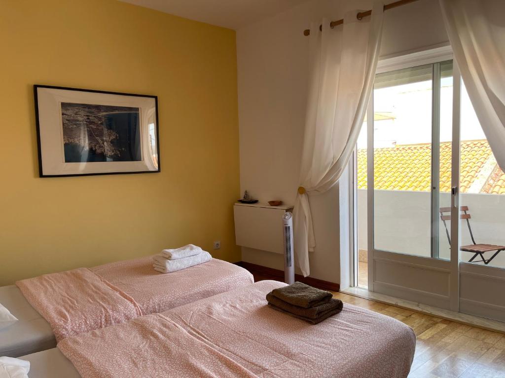 a bedroom with two beds and a large window at Casa da Aldeia - Guest House in Odiáxere