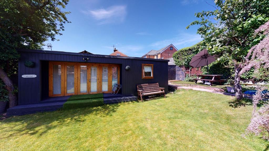 a small black house with a bench in a yard at Cosy 1 bed Garden Lodge Close to Nottingham City Centre in Nottingham