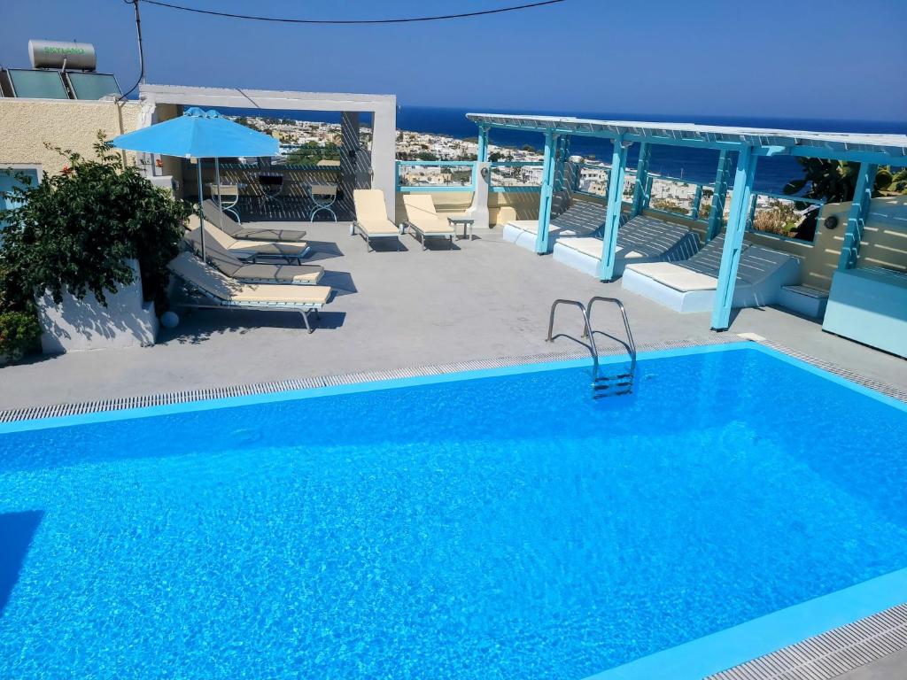 a large blue swimming pool with chairs and an umbrella at Villa Anneta in Kamari