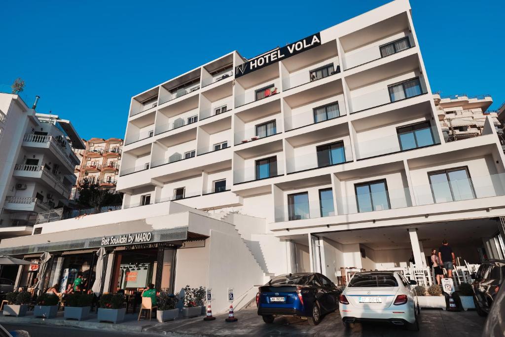un edificio de hotel con coches estacionados frente a él en Hotel Vola, en Sarandë