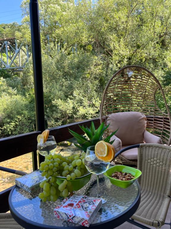 a table with grapes and wine glasses on a balcony at Kuća na vodi Ilma in Kulen Vakuf