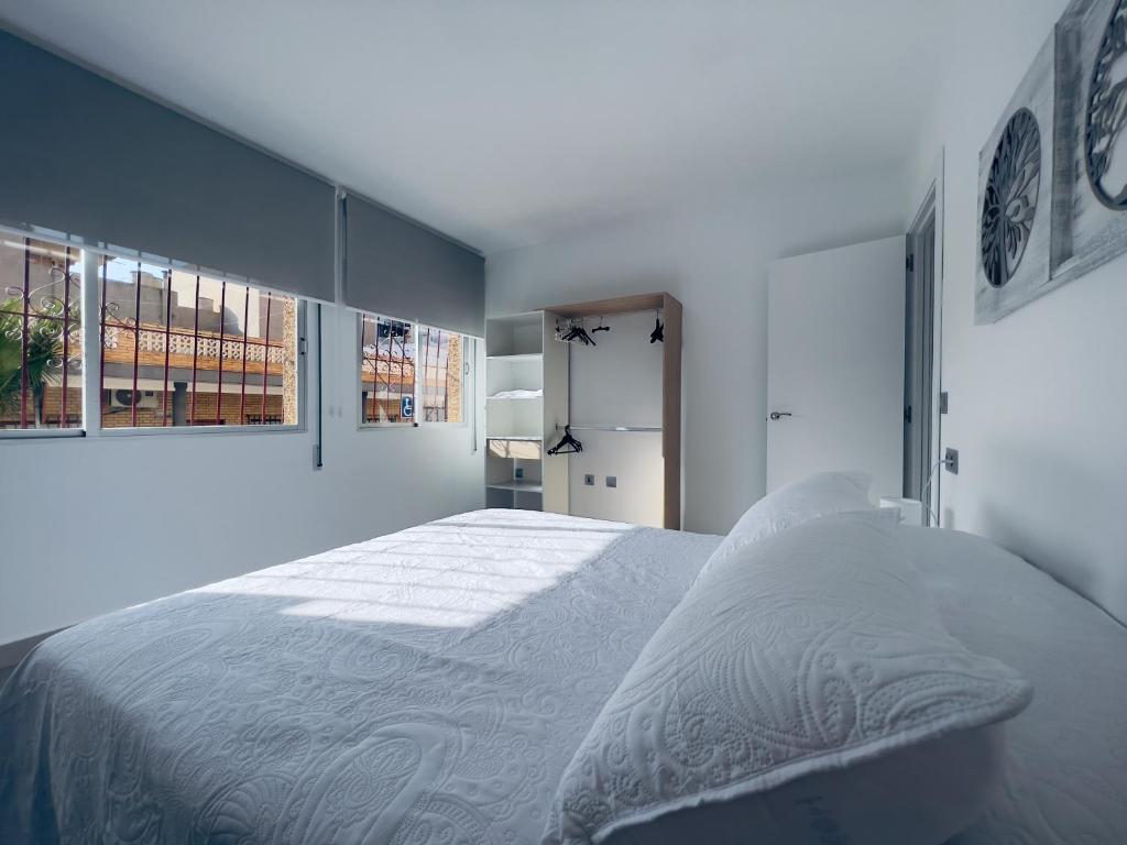 a white bedroom with a large bed and windows at Paradise Sol Apartamento en Los Alcázares in Los Alcázares