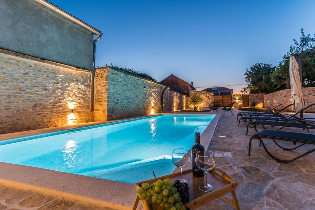 a pool with a table with grapes and wine glasses at Luxury Villa Cortile in Benkovac
