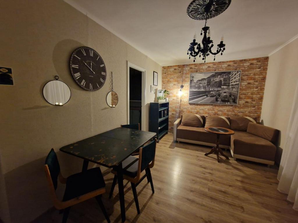 sala de estar con mesa y reloj en la pared en Apartament Zielony, en Gdansk