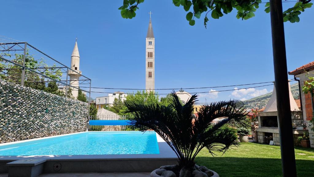 een zwembad met een palmboom in een tuin bij Apartman Karla in Mostar