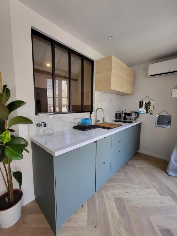 a kitchen with blue cabinets and a large window at Appartement des Augustins in Aix-en-Provence