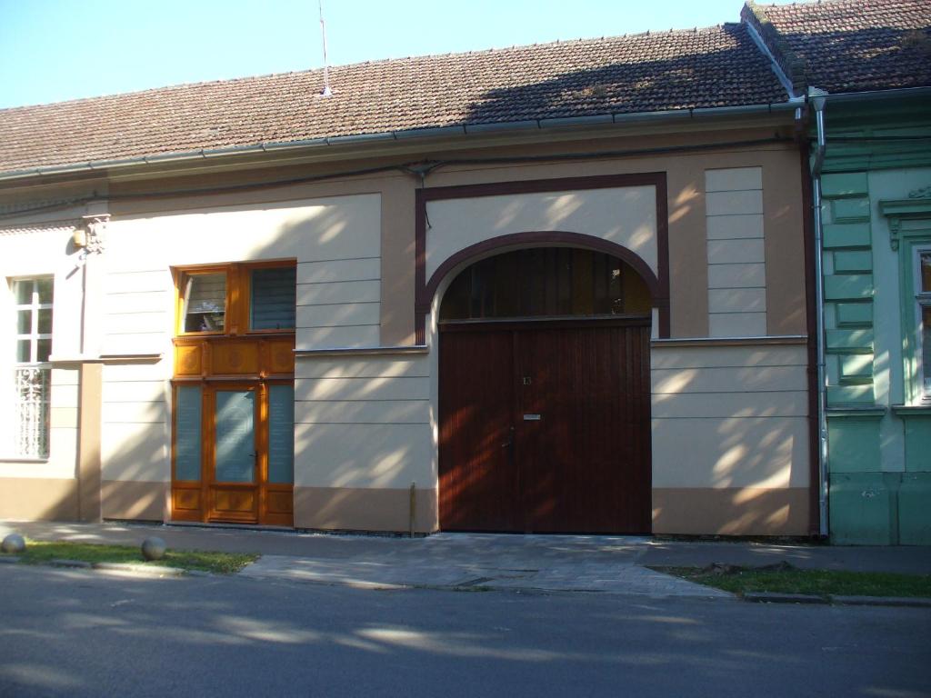 un edificio con una puerta marrón y un arco en Berta Apartman, en Senta