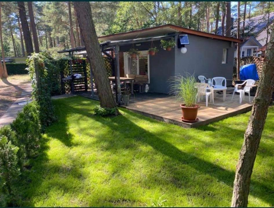 un patio trasero con terraza y una casa con mesa y sillas en Domek letniskowy Pogorzelica en Pogorzelica