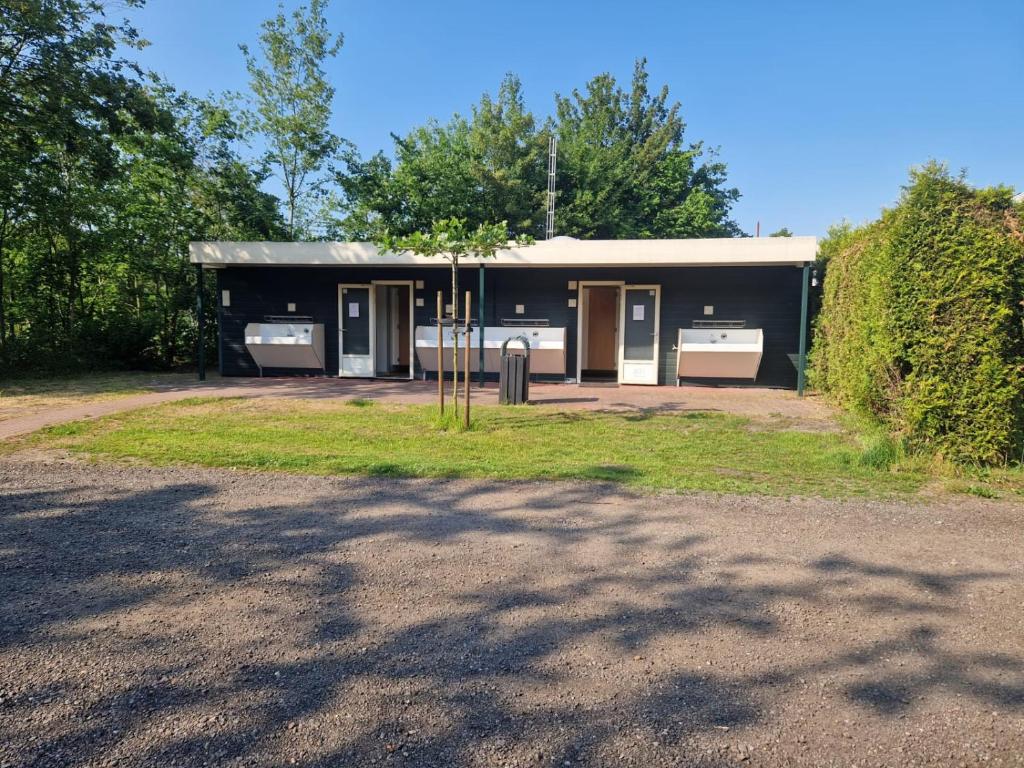 een zwart gebouw met twee wastafels in een tuin bij Blokhut Plus Camping Alkenhaer in Appelscha