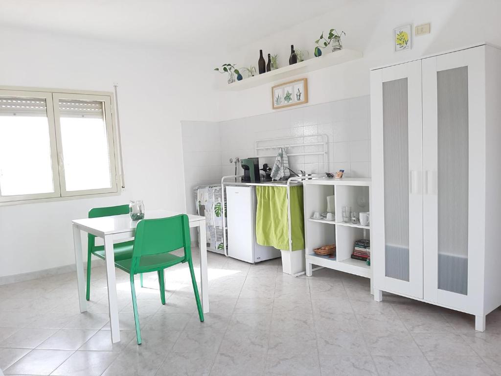 a white kitchen with a table and green chairs at Rosso di Sera Loft in Menfi