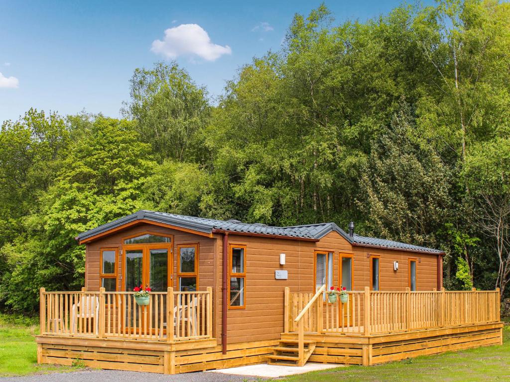 a large wooden cabin with a large deck at Wildhaven Lodge in Dalbeattie