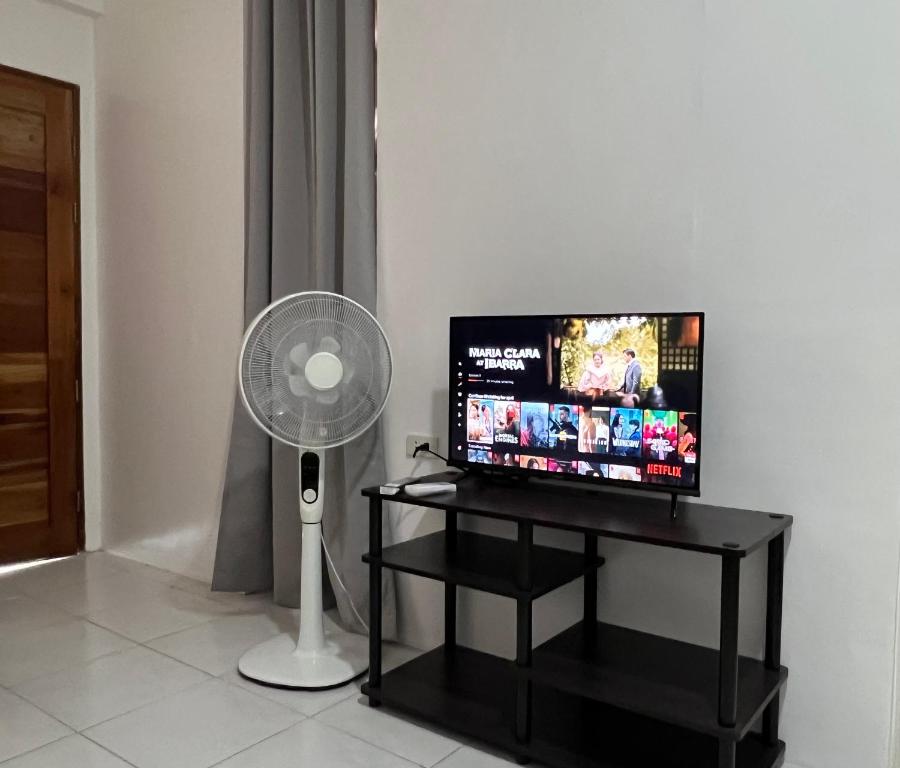 a flat screen tv sitting on a table with a fan at Reinhardshausen Suites and Residences- Lovely Air-Conditioned Units in Tuguegarao City
