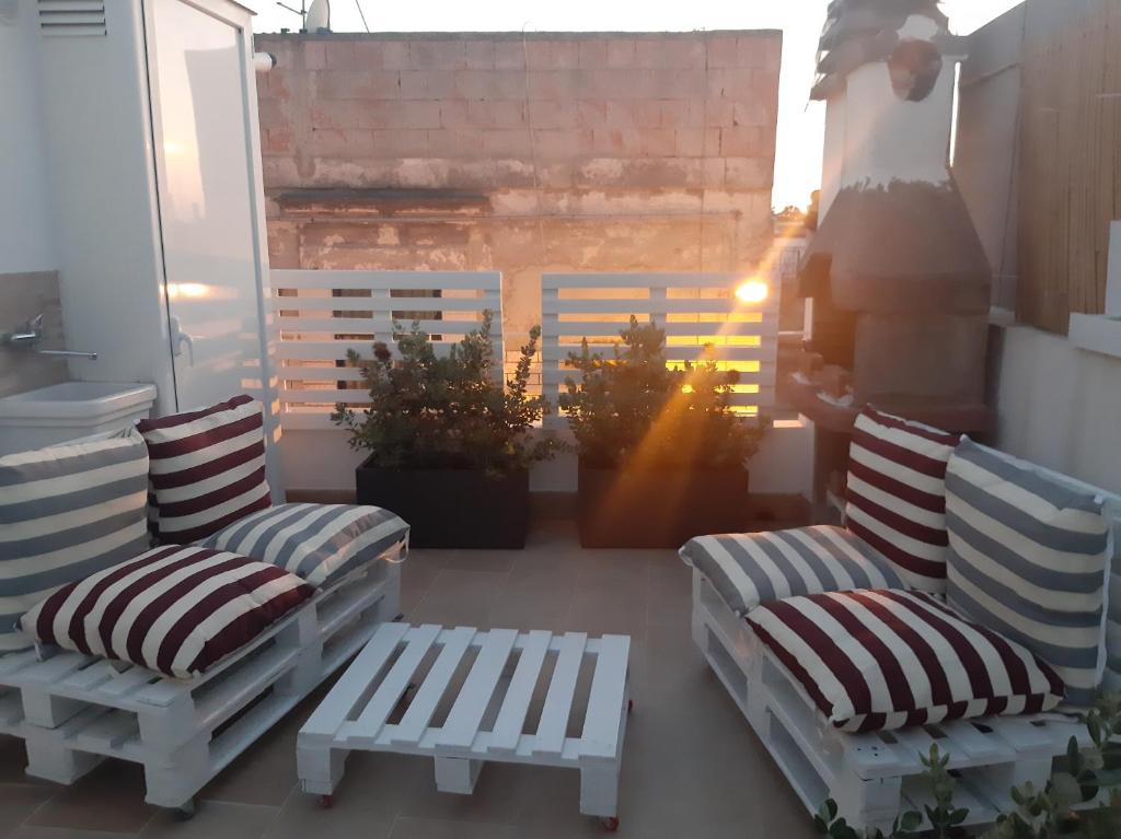 two chairs and a bench on a balcony with the sunlight at loft giulia in Bari