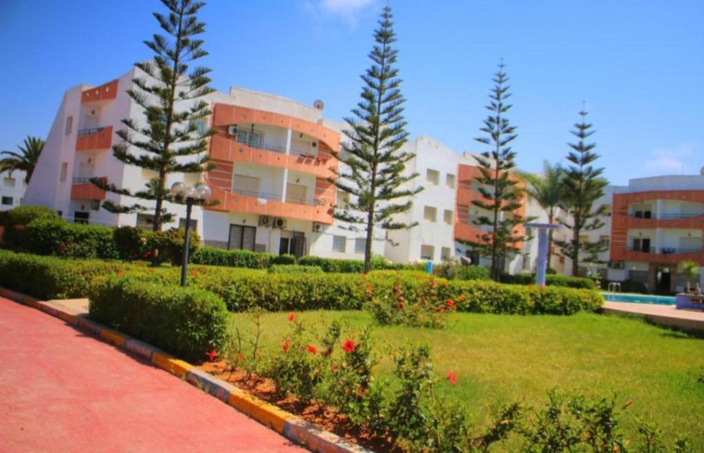 un parque frente a un edificio con árboles y flores en Les jardins de l'atlantique en Mohammedia