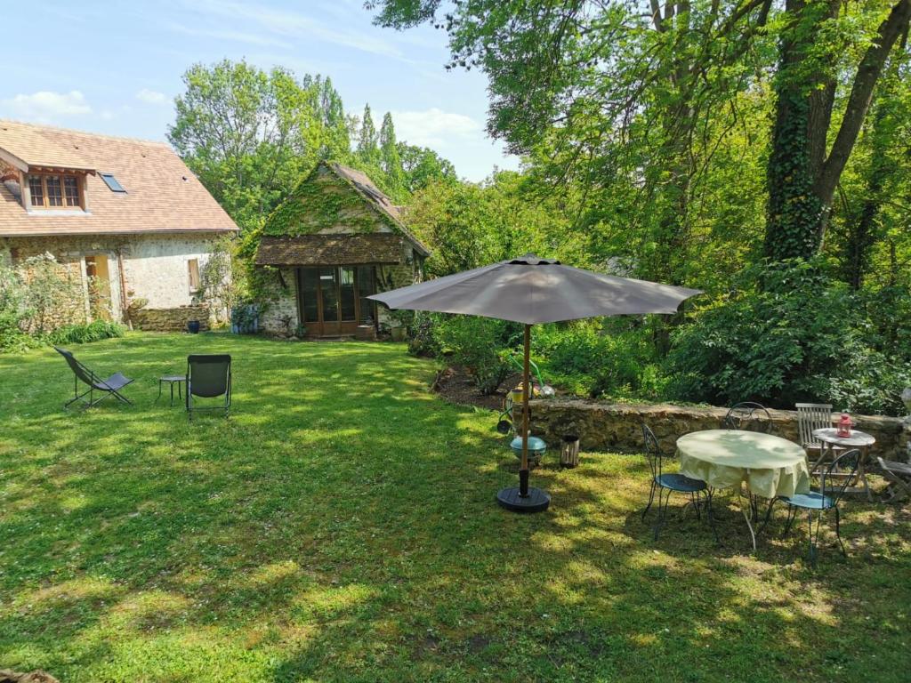 an umbrella in a yard with a table and chairs at Domaine de la Folicoeur in Sainte-Colombe-près-Vernon