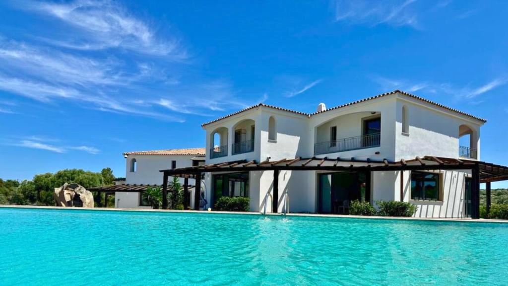 une villa avec une piscine en face d'une maison dans l'établissement La Smeraldina Resort, à Santa Teresa Gallura