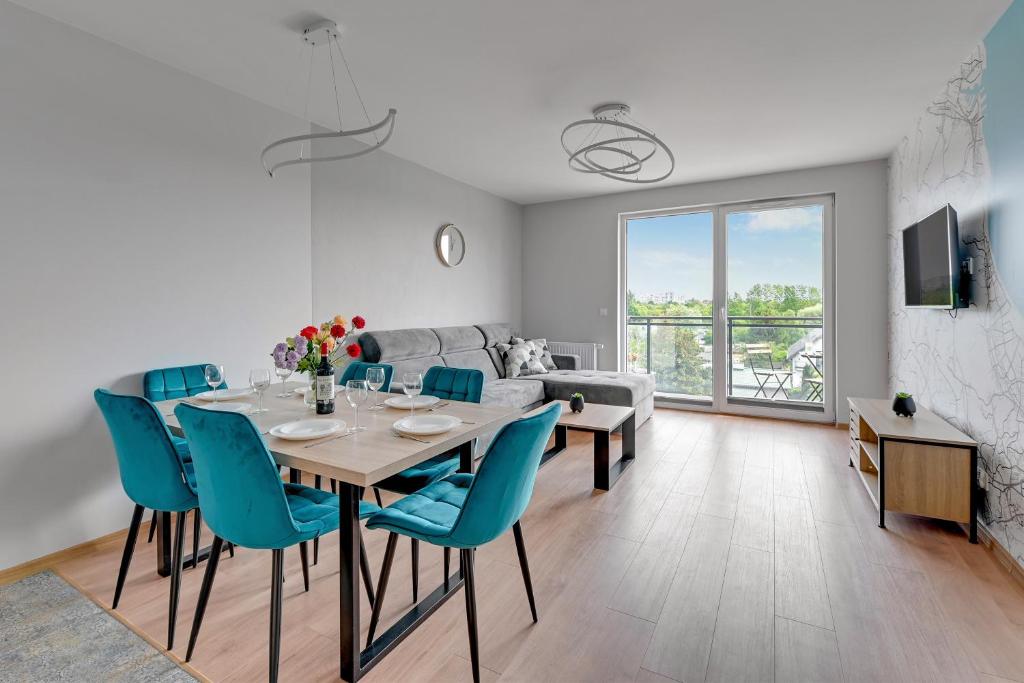 a dining room with a table and blue chairs at Apartament Letnica Białe Piaski by TriApart in Gdańsk