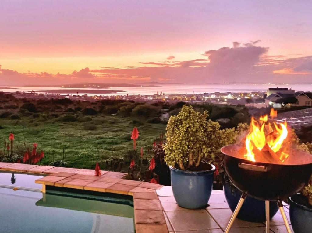 a fire pit next to a swimming pool with a sunset at The Boulders Langebaan in Langebaan