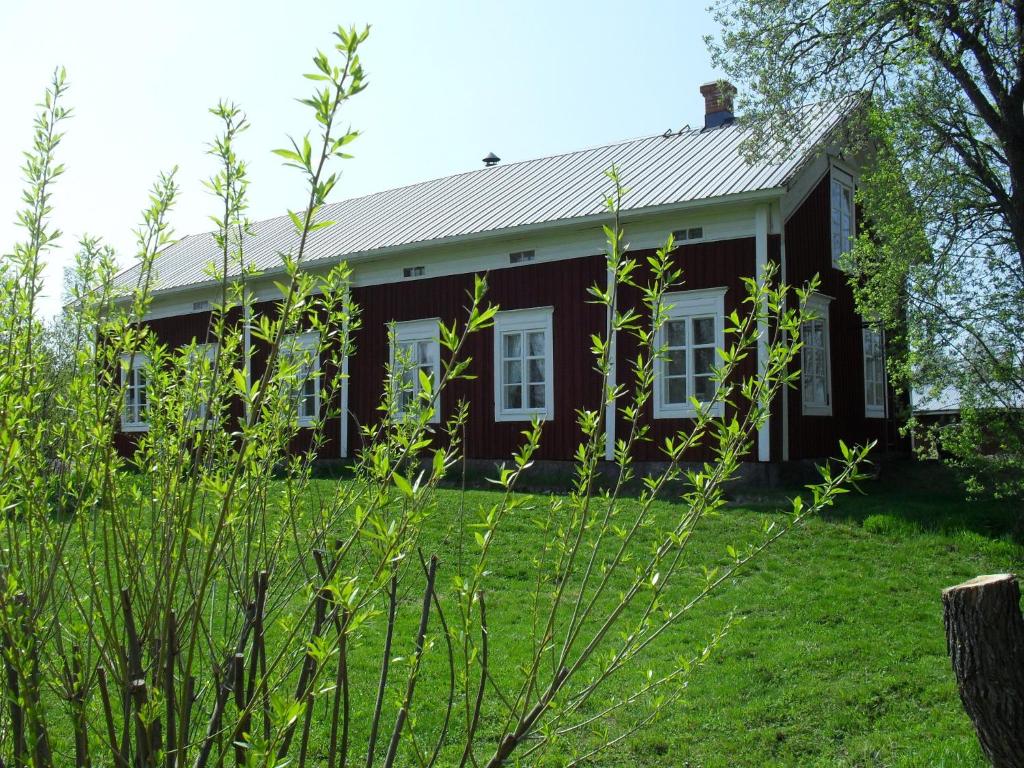 een rood huis met witte ramen en groen gras bij Old Farmhouse Wanha Tupa in Kristiinankaupunki