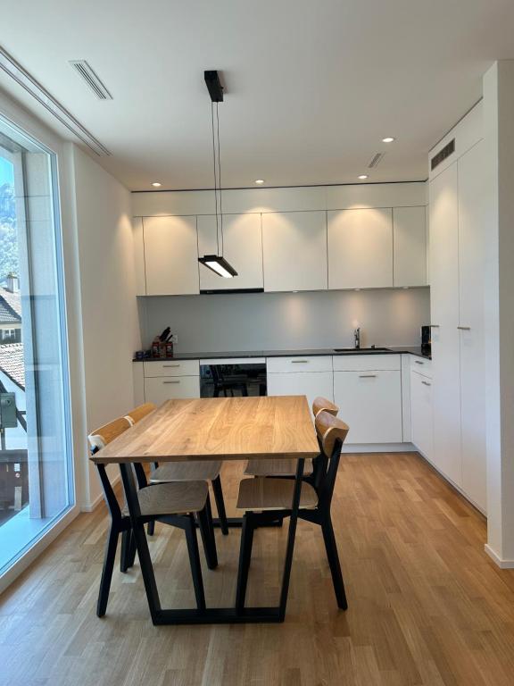 a kitchen with a wooden table and chairs at The R Apartment Passwang, KLIMA, NEU, Balkon, Parking in Balsthal